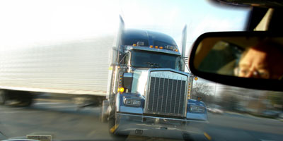 A large truck bearing down on a passenger car.